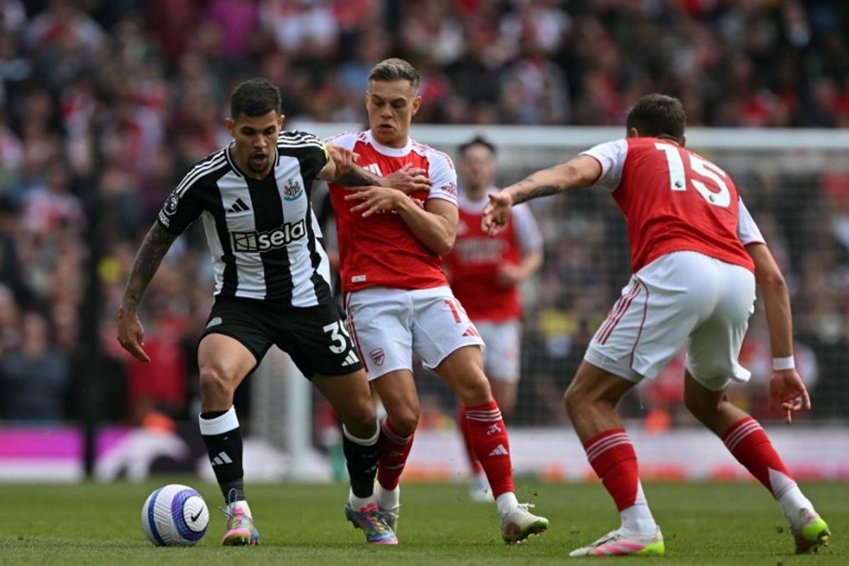 Newcastle United's Brazilian midfielder #39 Bruno Guimaraes (L) vies with Arsenal's Belgian midfielder #19 Leandro Trossard (C) and Arsenal's Polish defender #15 Jakub Kiwior (R) during the English Premier League football match between Arsenal and Newcastle United at the Emirates Stadium in London on May 18, 2025. Glyn KIRK / AFP