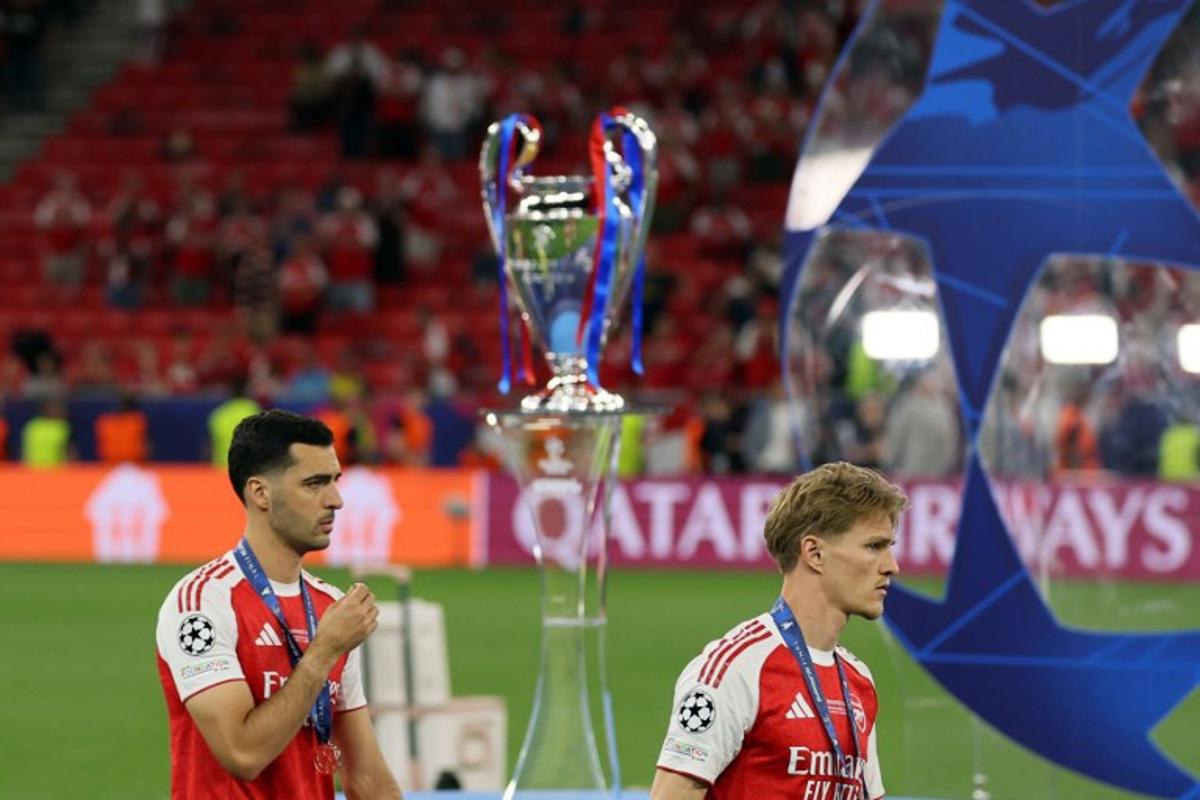 Arsenal's Spanish midfielder #23 Mikel Merino (L) and Arsenal's Norwegian midfielder #08 Martin Odegaard walk past the trophy following the UEFA Champions League final football match between Paris Saint-Germain (PSG) and Arsenal FC at the Puskas Arena in Budapest on May 30, 2026. Odd ANDERSEN / AFP
