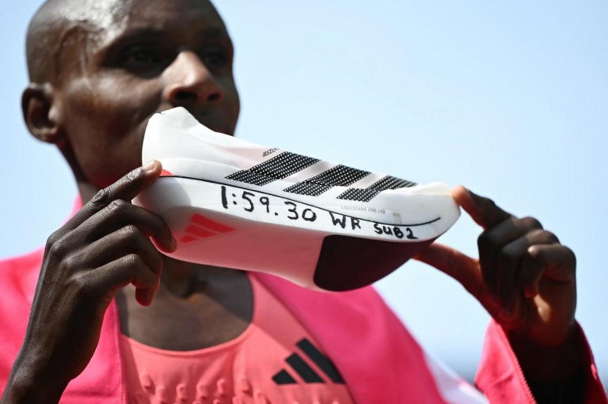 Kenya's Sabastian Sawe poses with his new world record time written on his running shoe at the finish of the 2026 London Marathon in central London on April 26, 2026. Kenya's Sabastian Sawe broke the two-hour mark for the first time in history on Sunday in winning the London Marathon. JUSTIN TALLIS / AFP