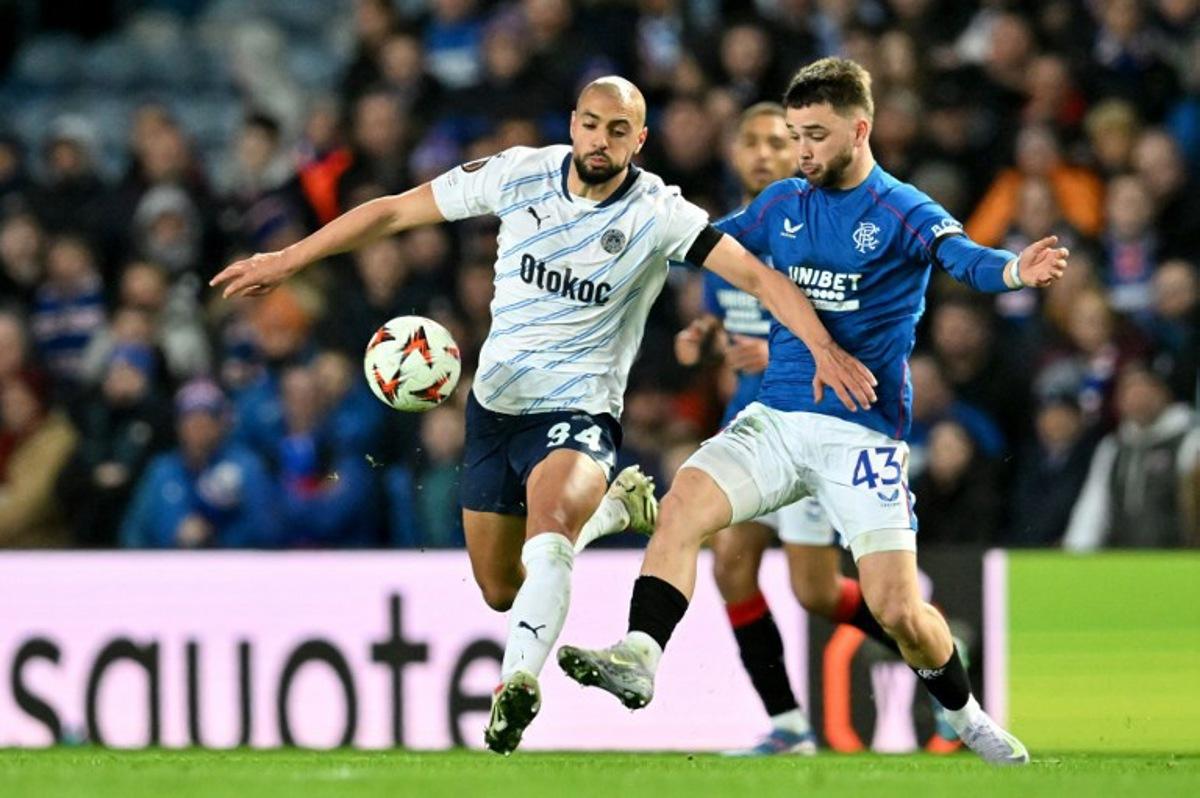 Fenerbahce's Brazilian striker #94 Talisca battles for the ball with Rangers' Belgian midfielder #43 Nicolas Raskin during the UEFA Europa League second-leg round of 16 football match between Rangers and Fenerbahce SK at the Ibrox Stadium in Glasgow on March 13, 2025. ANDY BUCHANAN / AFP